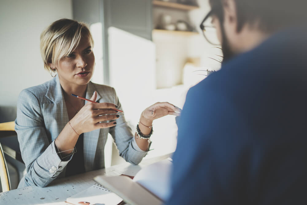 Coworkers working process at home.Young blonde woman working together with bearded colleague man at modern home office