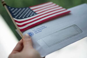 Envelope from USCIS (United states citizenship and immigration Services) and Flag of USA in left Hand