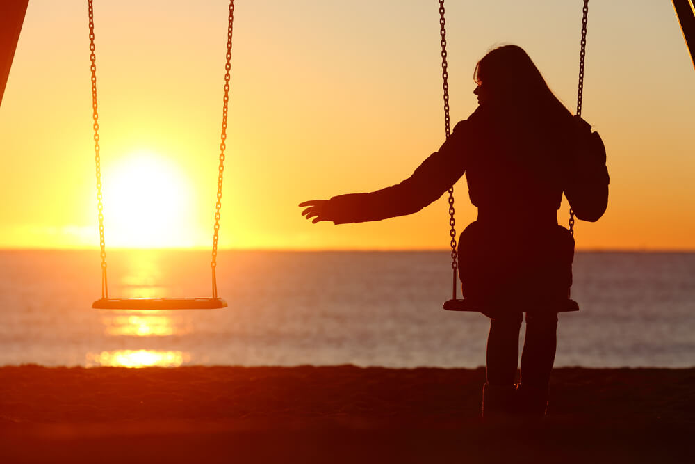 widow alone missing while swinging on the beach at sunset.