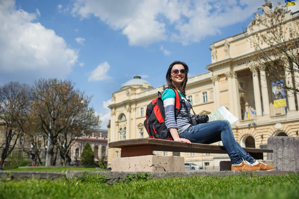 young happy attractive exchange student girl having fun in town visiting Lviv city reading tourist guide book having fun outdoors in tourism and travel vacation concept